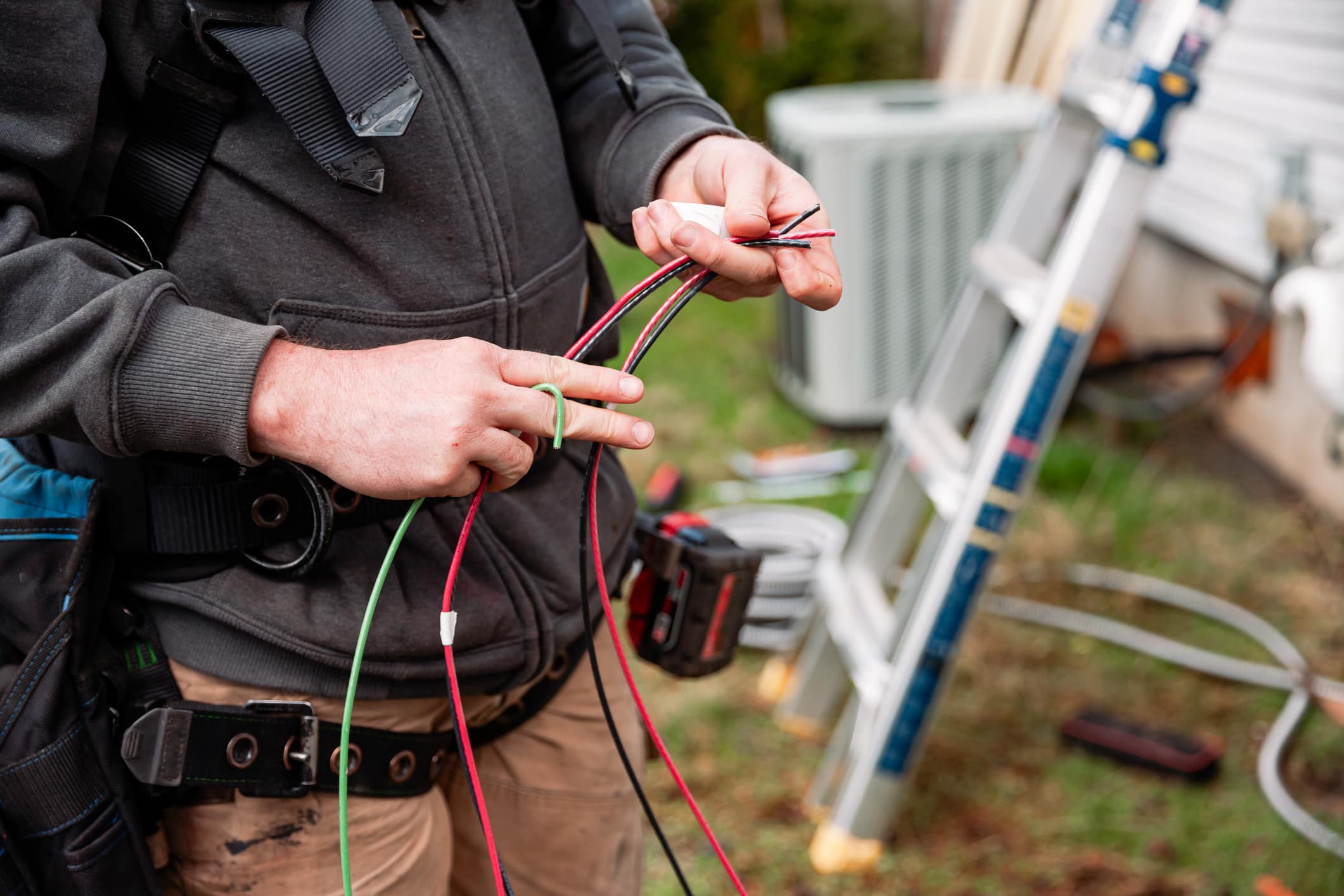 A professional solar technician installing a Solar Panel Electric Box on the side of a house