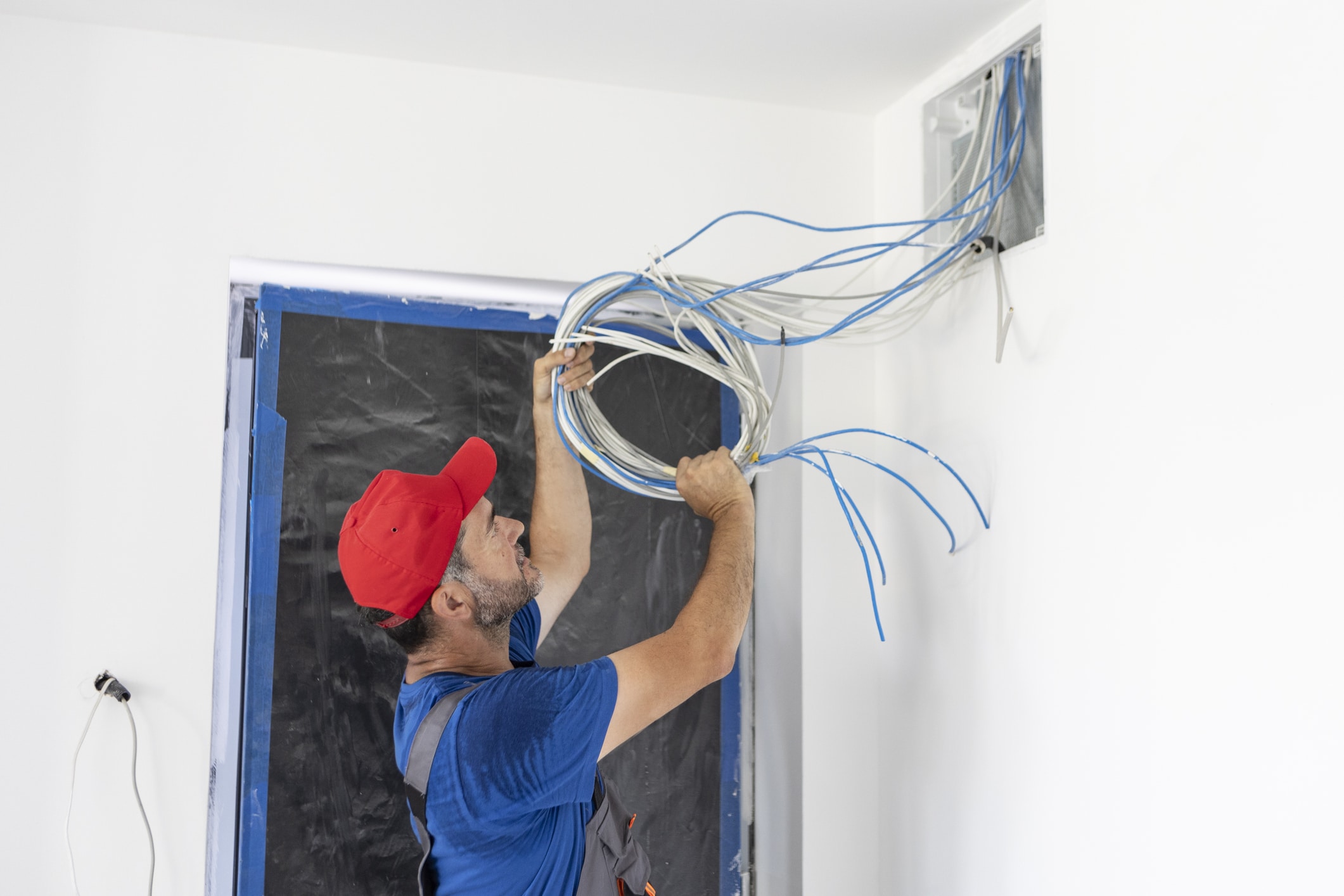 Electrician on a construction site of a new house, instaling cable TV and internet.
