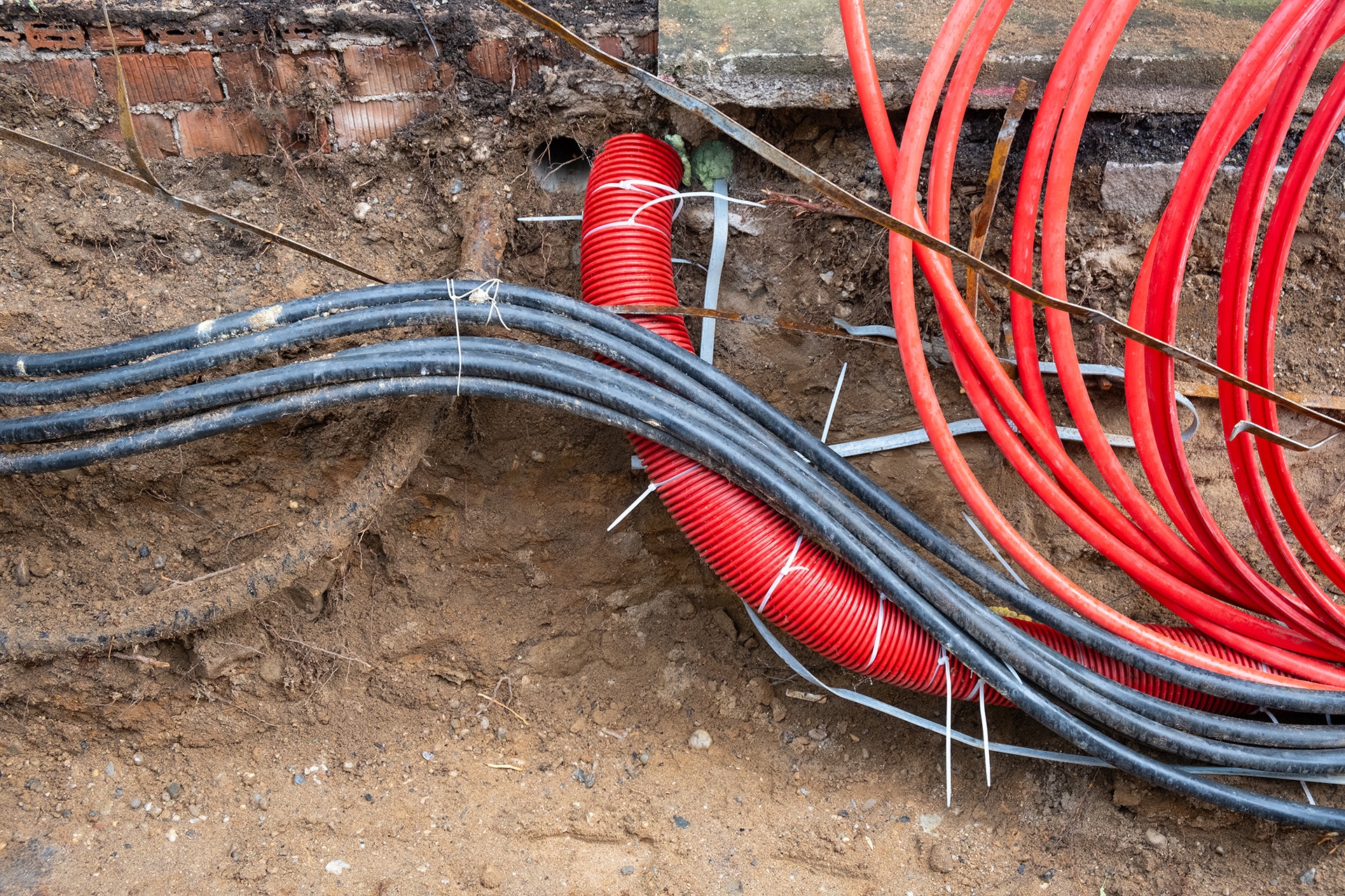 Electric and high-speed Internet Network cables in red corrugated pipe are buried underground