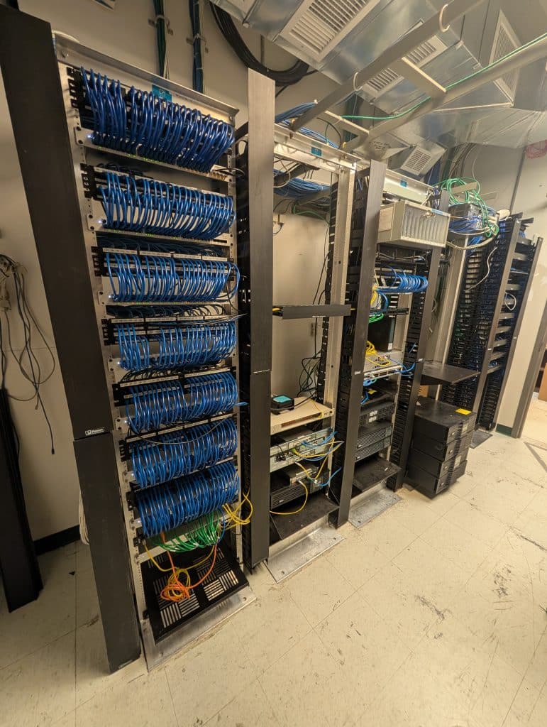 After: network racks with neatly routed patch cables and clear access to equipment.